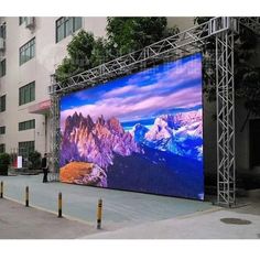 an outdoor stage set up in front of a building with mountains on the side and blue sky