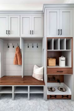 a white mud room with wooden shelves and coat racks