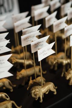 there are many small gold animals on the table with place cards in them for guests to sign