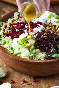 someone pouring dressing into a salad in a bowl