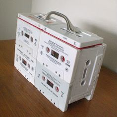 four white cassettes stacked on top of each other in front of a wall mounted clock