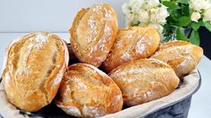 a basket filled with lots of bread on top of a white table next to flowers