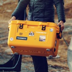 a man holding a yellow case with stickers on it