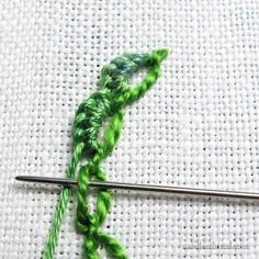 the green thread is being used to make a crochet pattern on white fabric