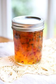 a jar filled with hot pepper jelly sitting on top of a white table next to a red frame