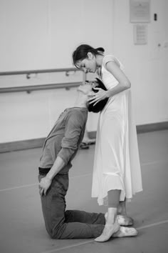 a man kneeling down next to a woman in a dance studio while holding her head