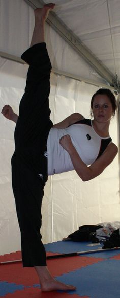 a woman doing a handstand on top of a blue mat in a tent