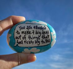 a hand holding a rock with a quote on it