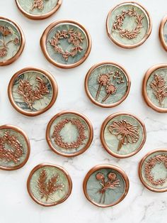 many different types of buttons on a marble surface with copper trimmings and floral designs