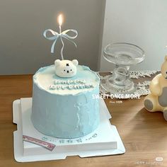 there is a cake with a teddy bear on it and a candle in the middle