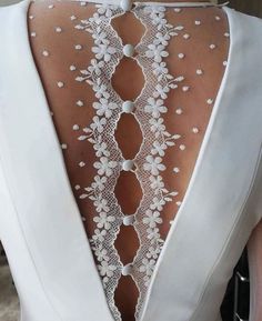 the back of a woman's wedding dress with white flowers and pearls on it