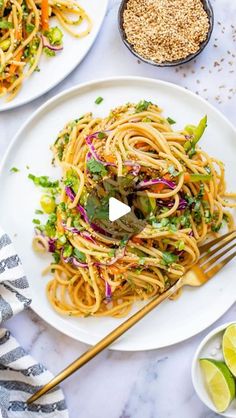 two white plates filled with noodles and veggies on top of a marble table