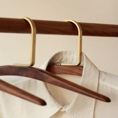 a wooden hanger holding clothes on top of a white shirt