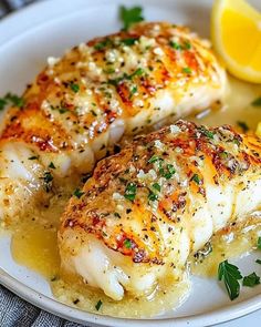 two pieces of chicken on a plate with lemons and parsley