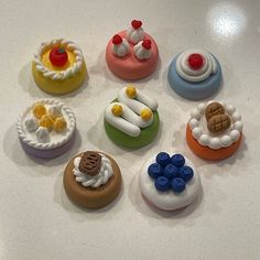 there are many small toy cakes on the counter top, each decorated with different shapes and colors