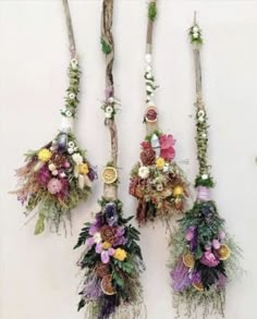 three bouquets of flowers are hanging on the wall next to some branches and twigs