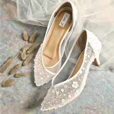 two pairs of wedding shoes sitting on top of a stone floor next to dried flowers