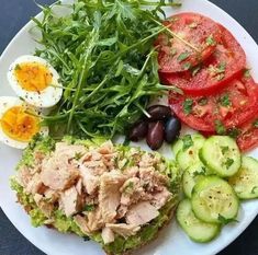 a white plate topped with meat, veggies and an egg