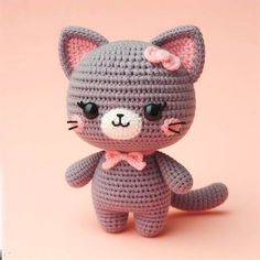 a small crocheted cat sitting on top of a pink surface