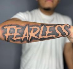 a man is holding his arm with the word fearless tattooed on it, in front of him