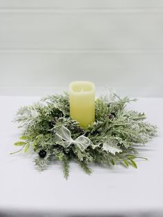 a white table topped with a candle and greenery