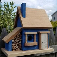 a blue bird house with wood stacked inside