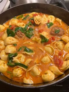 a skillet filled with pasta, meat and vegetables on top of a stovetop