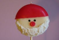 a close up of a cake on a stick with santa claus's face painted on it