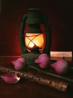 a candle is lit next to some flowers and an old pipe on a table with music notes