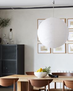 a dining room table with four chairs and a white paper lantern hanging from the ceiling