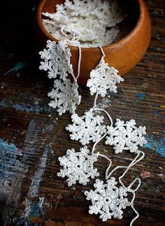 some white crocheted flowers in a wooden bowl