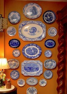 blue and white plates hanging on the wall next to a table with a lamp in front of it