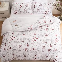 a bed with white sheets and red flowers on it