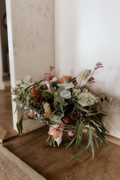 a bouquet of flowers sitting on top of a wooden table next to a white wall