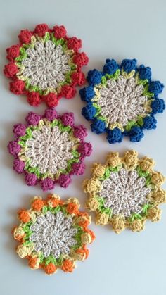 four crocheted coasters sitting on top of a table