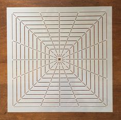 a white paper cut out with lines in the center on a wooden surface, showing an intricate design