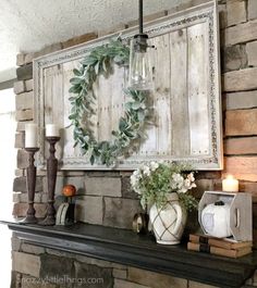 a mantel with candles, vases and flowers on it