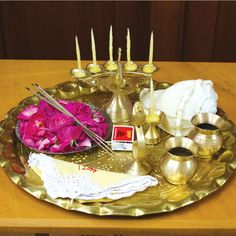 a brass tray with candles, flowers and tea in it on top of a wooden table