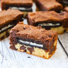 several pieces of chocolate and oreo cookie bars on a white wooden table with one cut in half