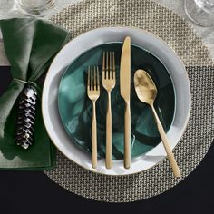 a white plate topped with silverware next to a green napkin and fork on top of a table