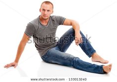 a young man sitting on the floor with his legs crossed and looking at the camera