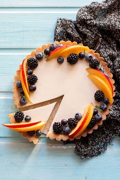 a cake with fruit on it and a knife stuck in the top one slice is ready to be cut