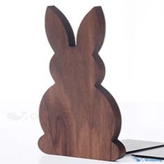 a wooden bunny sitting on top of a table next to a cell phone and pen