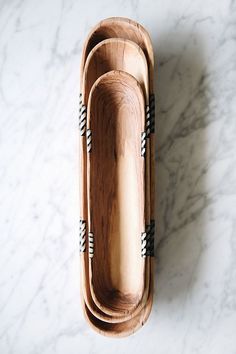 three wooden serving trays with black and white striped handles on a marble countertop