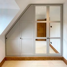 an attic bedroom with white walls and wooden flooring, built in to the ceiling