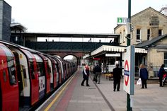 people are standing on the platform next to a red and white train at a station