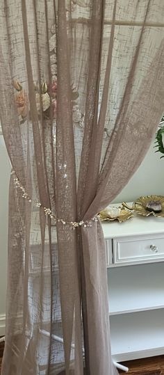 the sheer curtains are hanging in front of a window with flowers and pearls on them