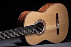 an acoustic guitar sitting on top of a black background with the strings still attached to it