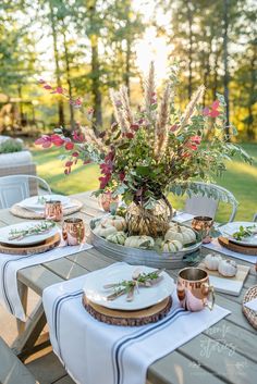 an outdoor table set with plates and place settings