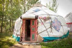 a yurt in the woods with an open door and some decorations on it's side